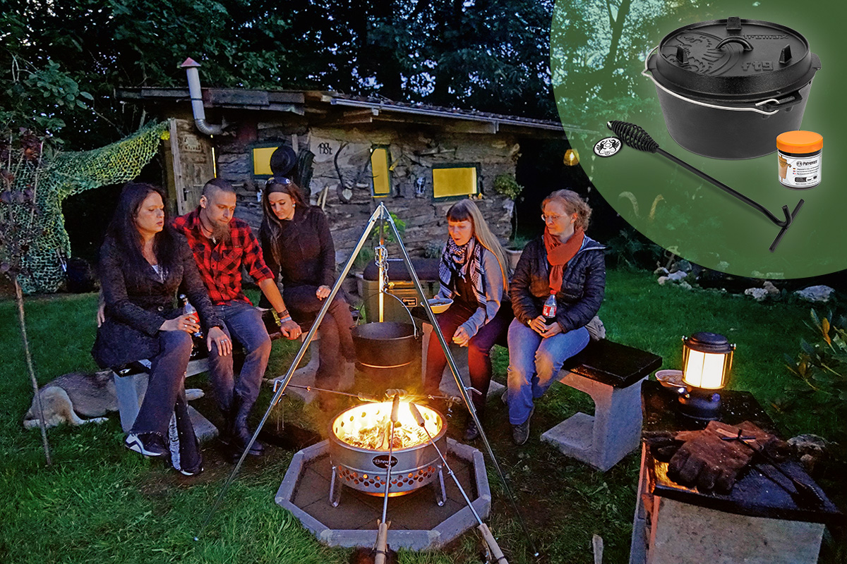 Fünf Personen sitzen in Abenddämmerung um Feuerstelle, Stockbrothalter im Vordergrund über Flamme, Dutch Oven an Dreifuß darüber